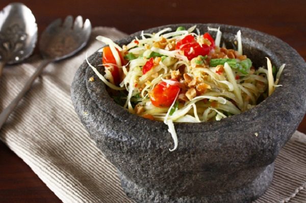 giã nhuyễn nguyên liệu làm nộm đu đủ xanh trong cối đá