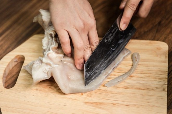 dùng dao cắt tai heo luộc thành miếng mỏng