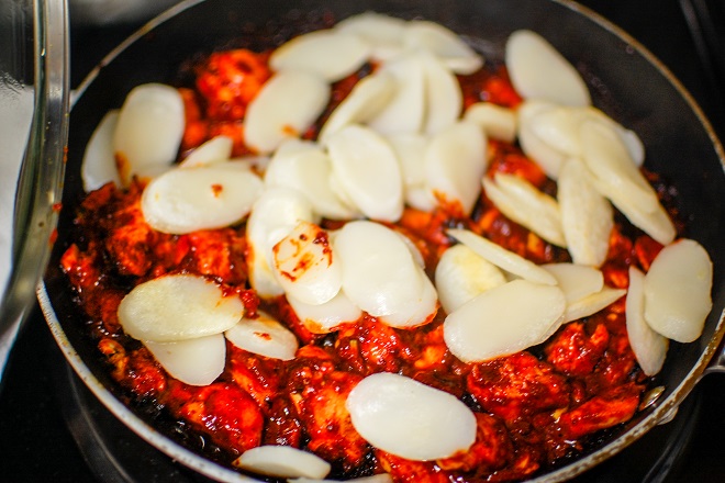 cho bánh gạo vào nấu chung với chảo gà cay